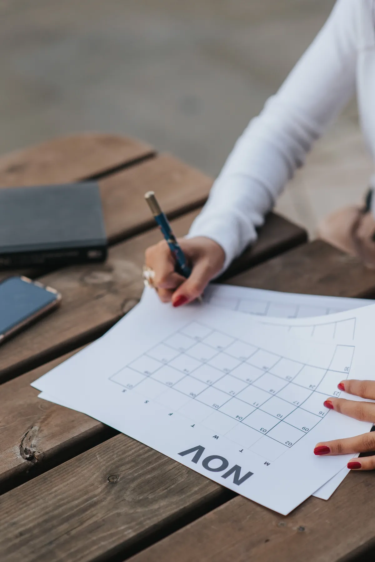 A woman writes notes on a monthly calendar.