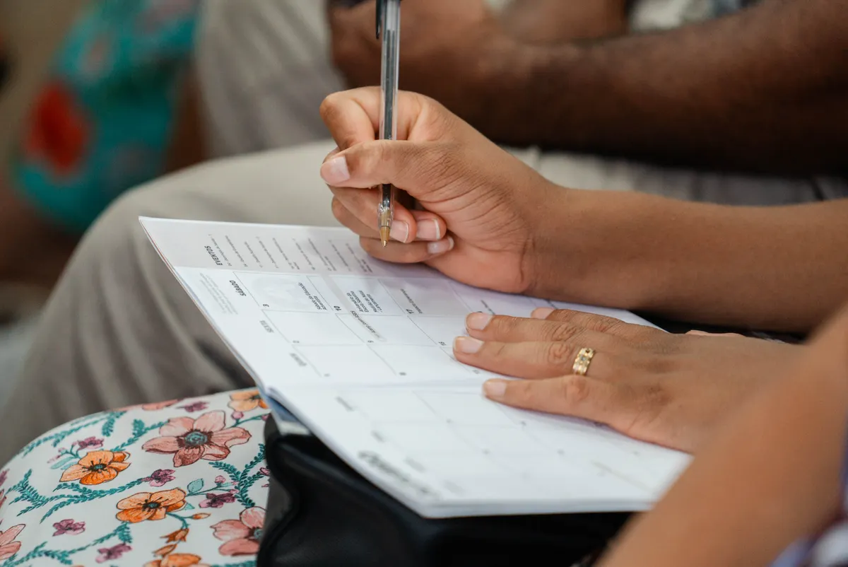 A hand records entries in a calendar planner.