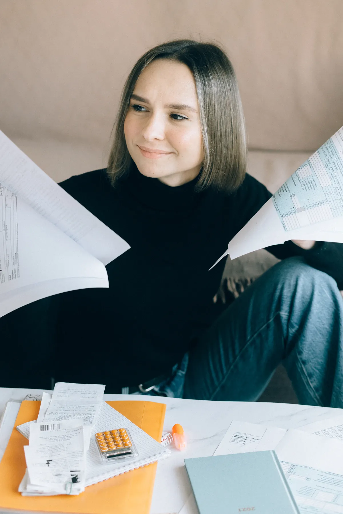 A woman reviews financial paperwork at a desk.