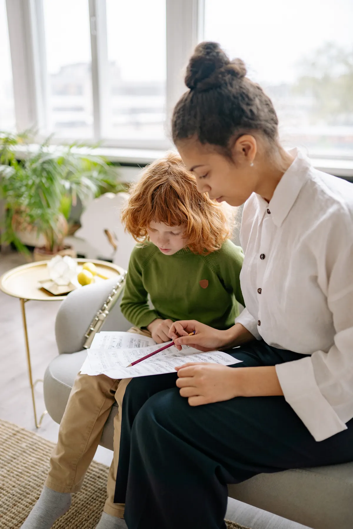 An adult provides one-to-one guidance as a child studies a text.