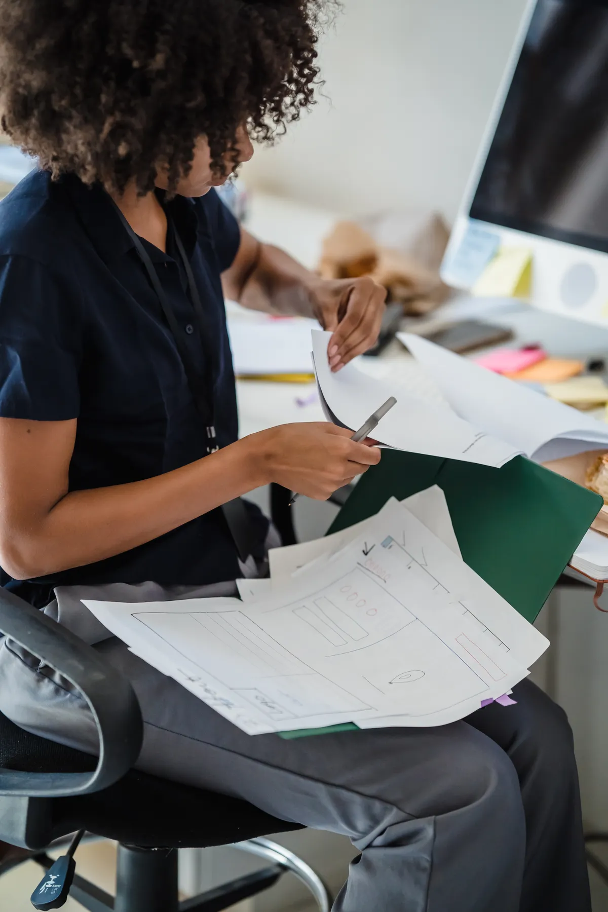 A woman prepares documents at her desk.