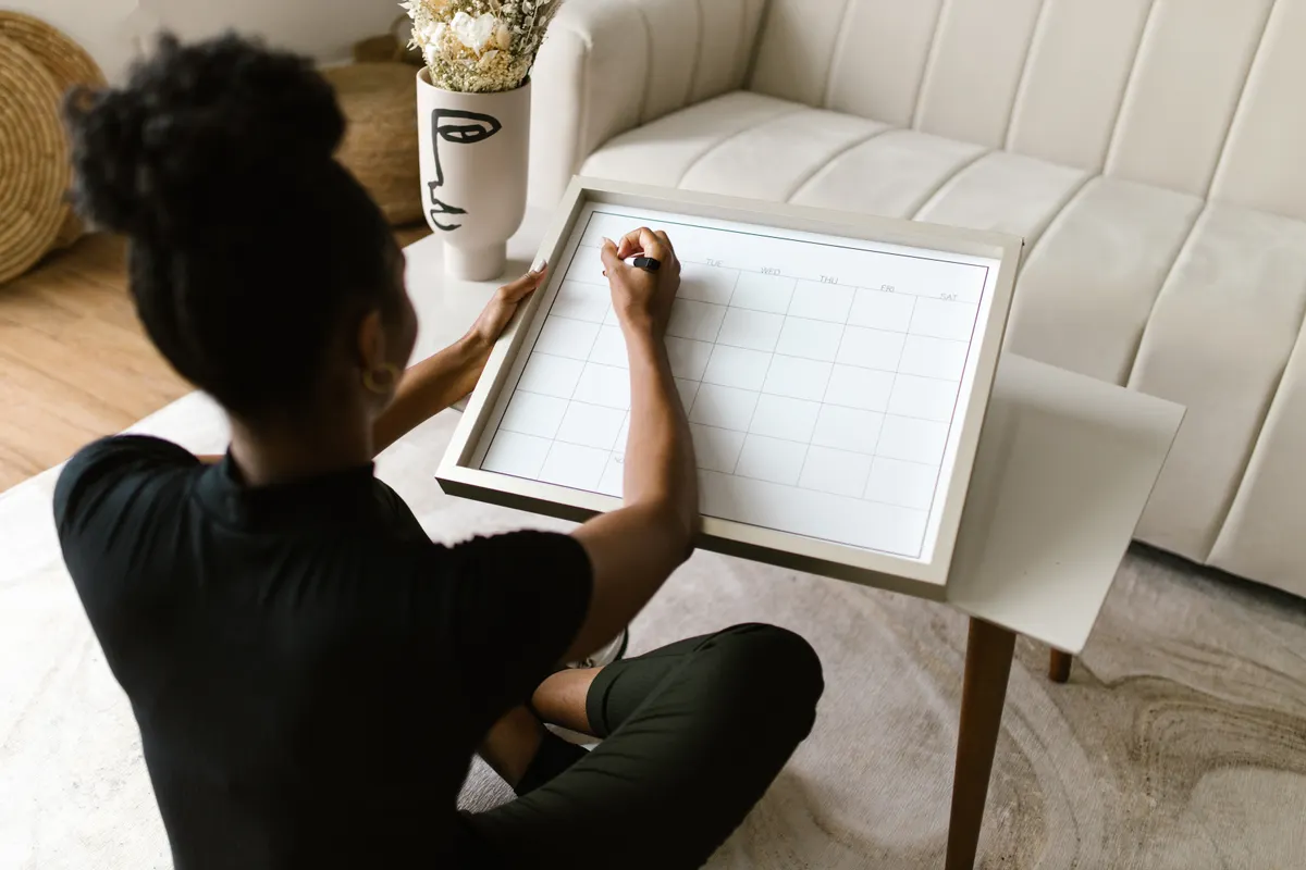A woman plans appointments on a calendar at home.