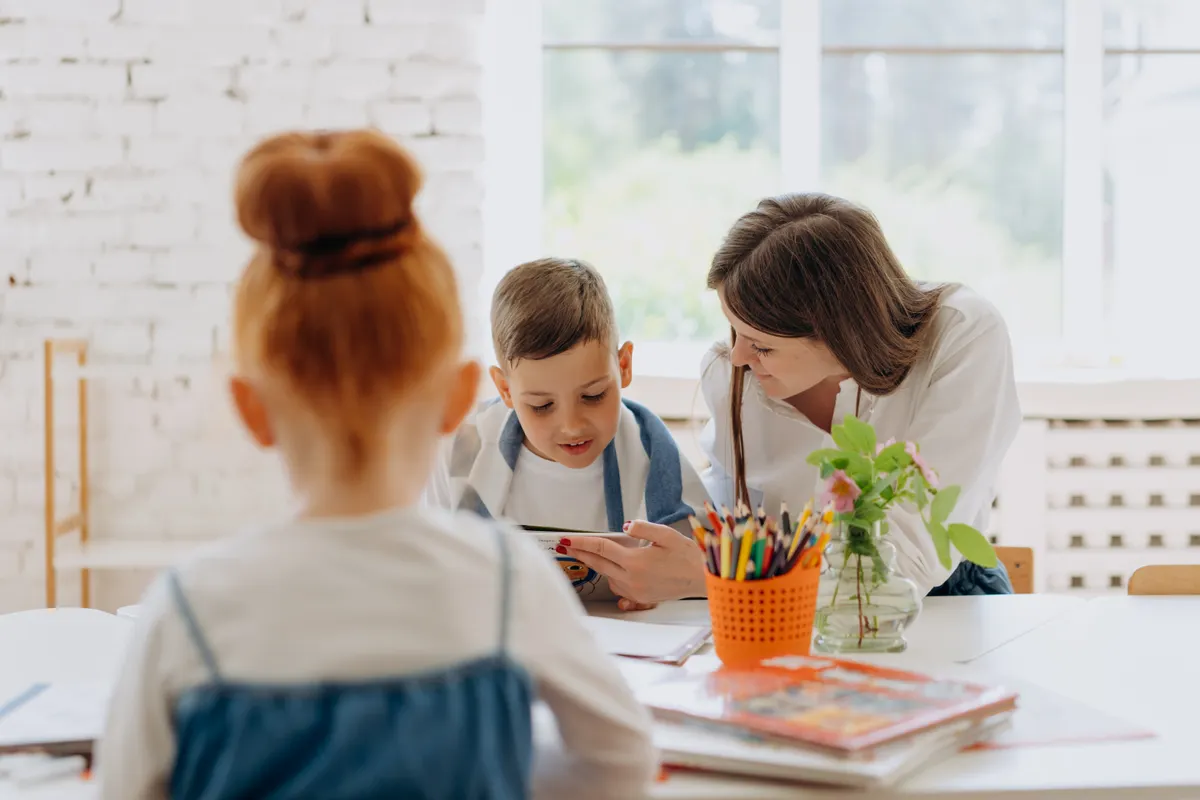 An adult and a boy share a book at a learning table.