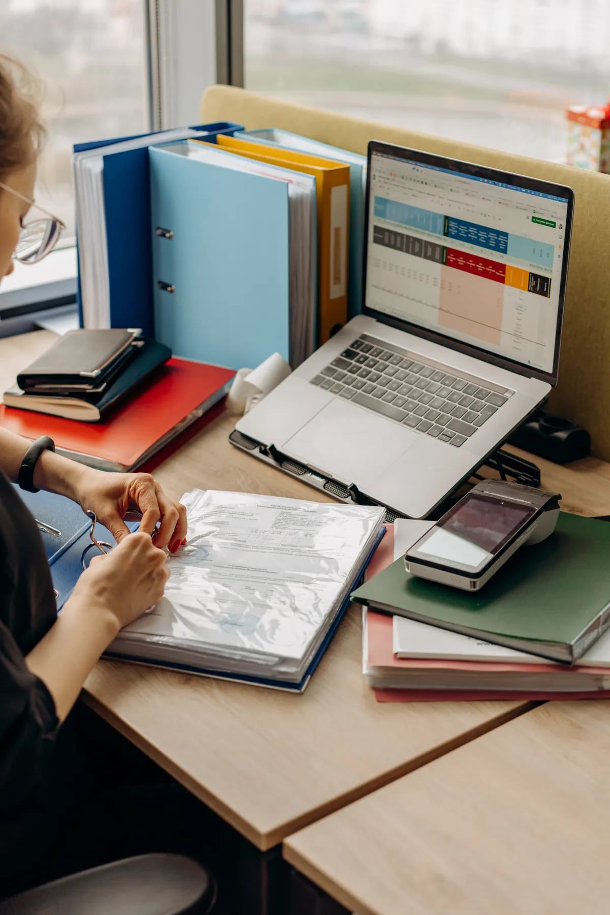 A woman organizes papers in a document binder.