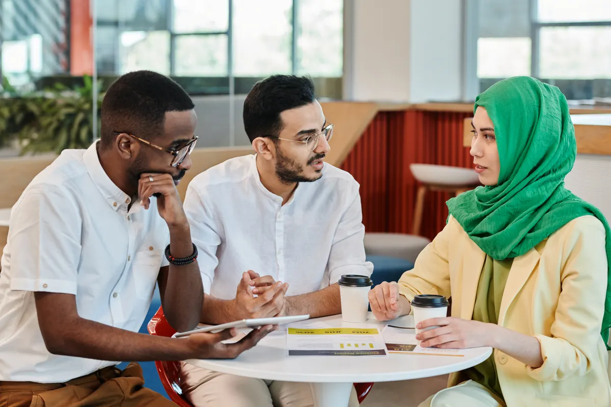 Three adults talk together around a table with notes.