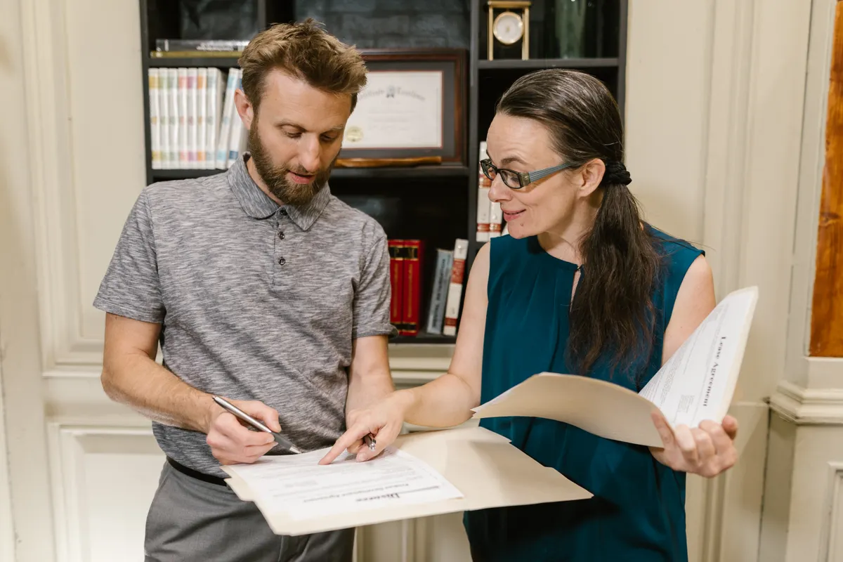 Two adults discuss paperwork at a table.