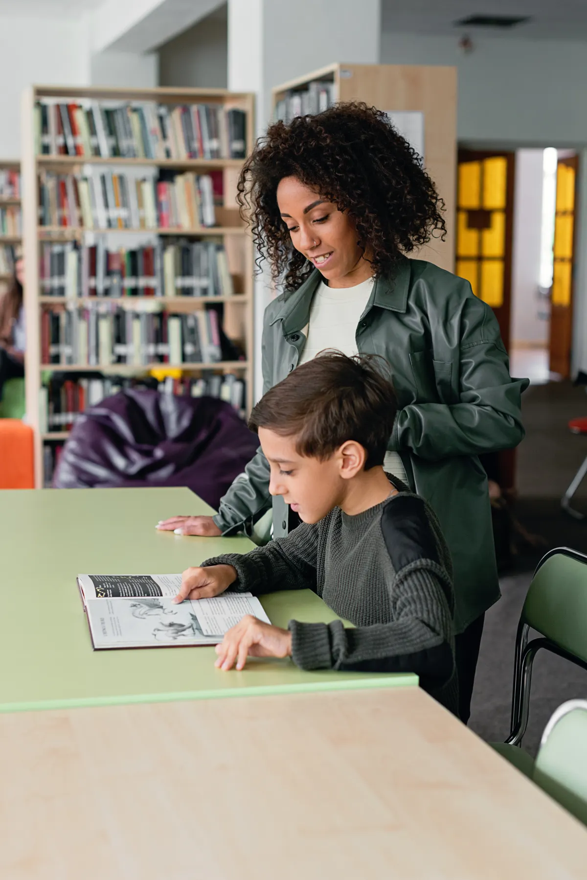 An adult and a child discuss a book in a library.