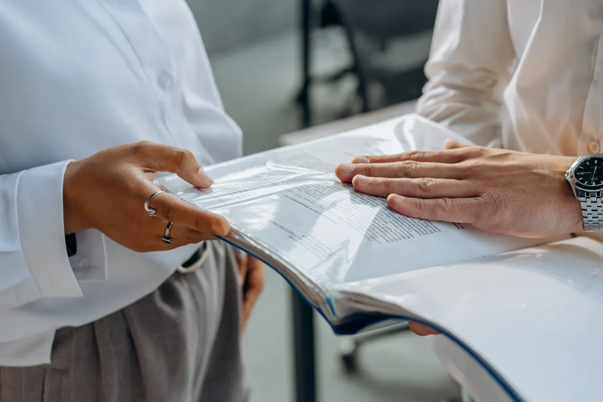 Two adults compare written documents during a discussion.
